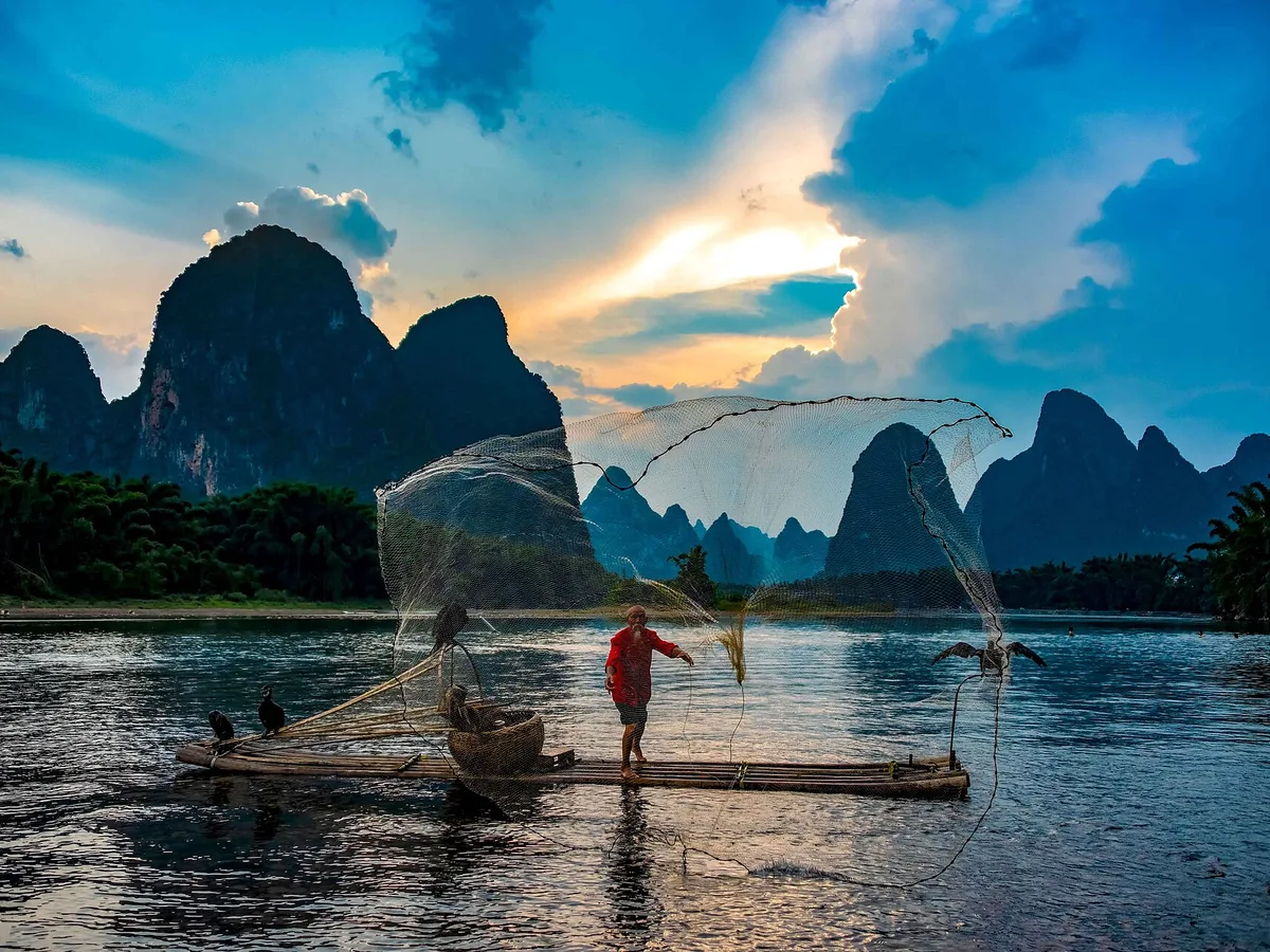 A cormorant fisherman on a bamboo raft on the Li River