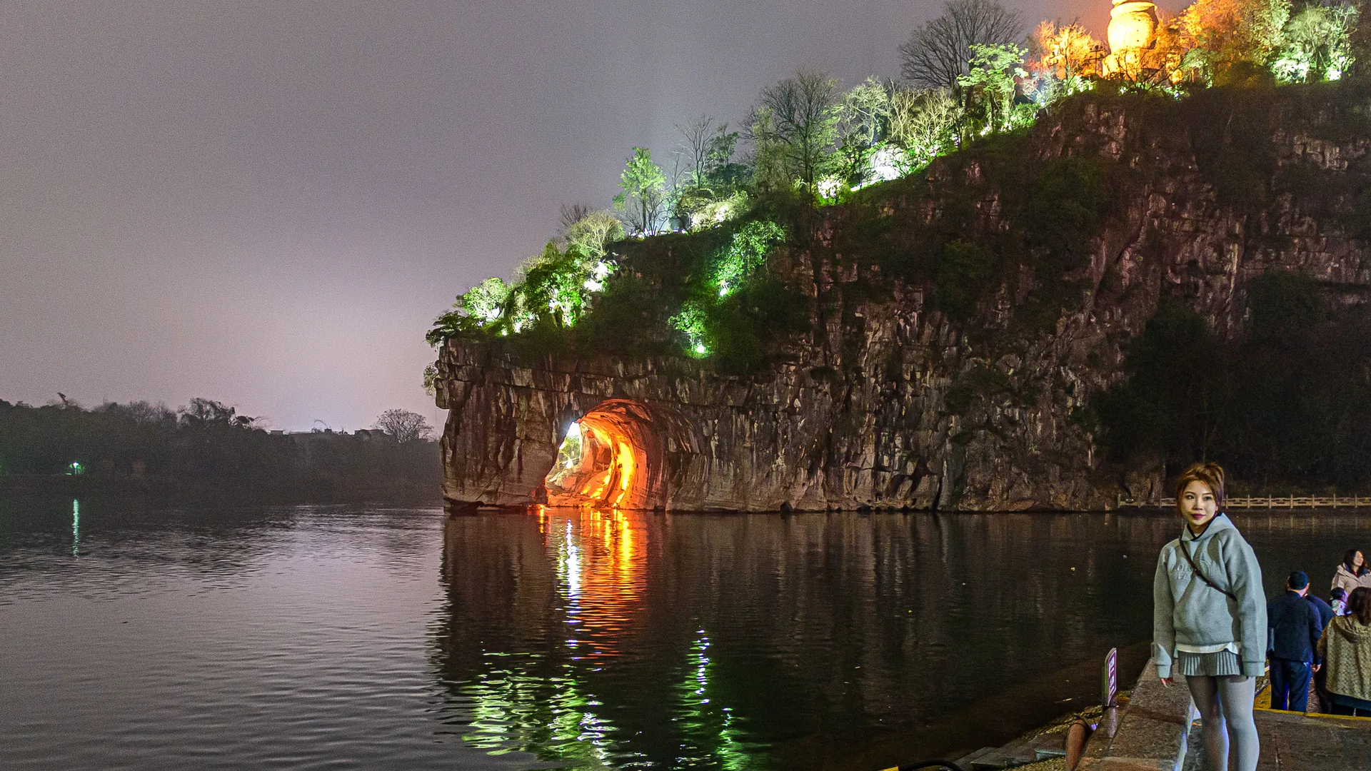 Illuminated karst mountains reflected in the Li River at night near Yangshuo, China, with coloured stage lighting on the water